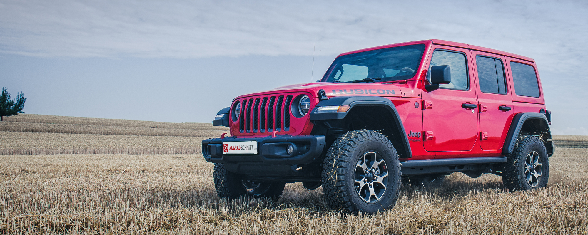 Roter Jeep Wrangler JL auf Feld im Sommer